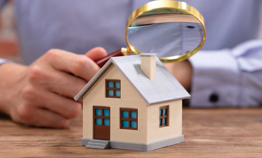 man looking at a model house with a magnifying glass